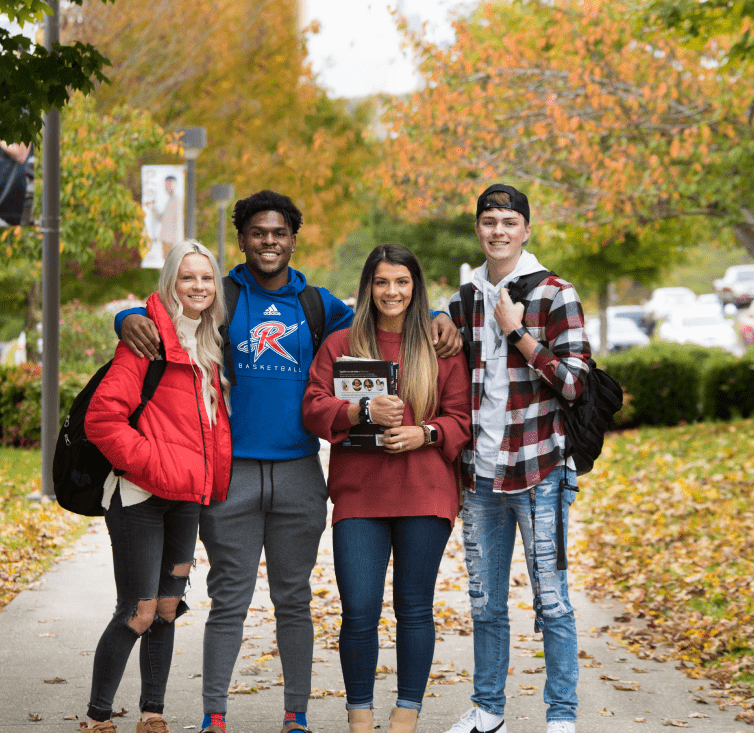 Four students standing together with arms around shoulders.